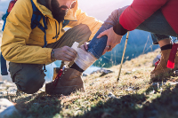 You can be an instructor (or learn from one) at Dash Class. A hiker getting first aid from another hiker in the mountains.